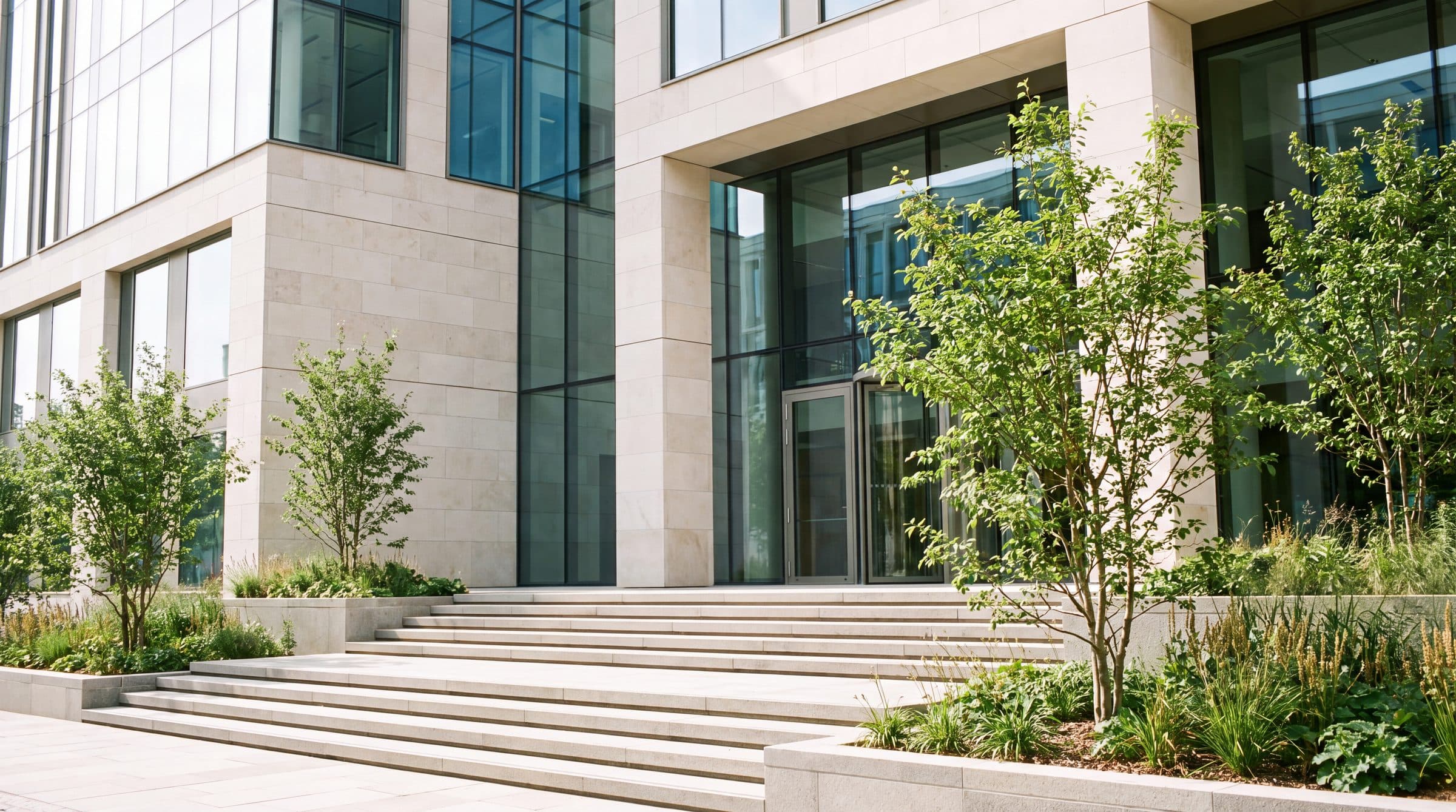 The entrance of a modern office building with steps and trees