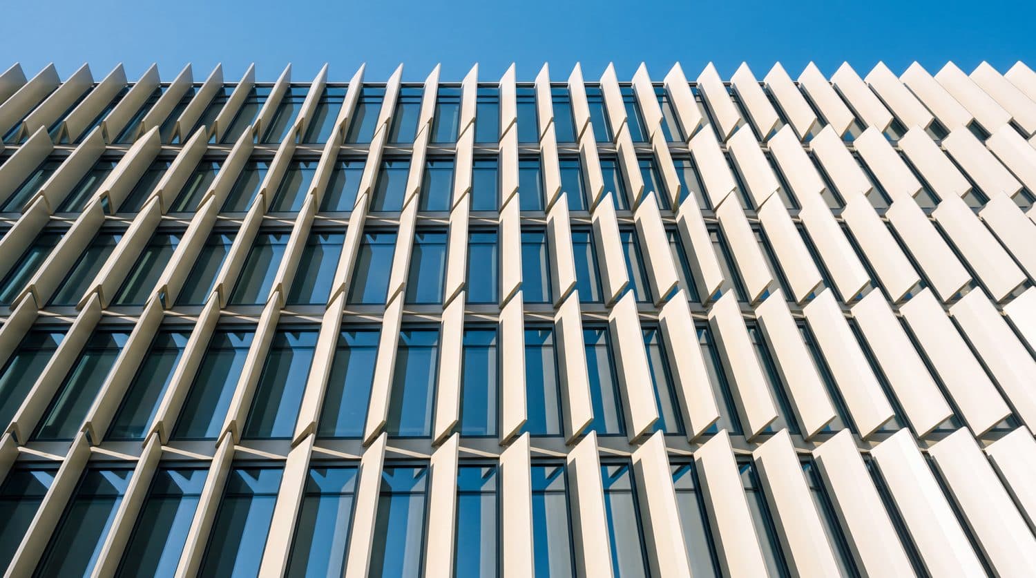 Glass facade with vertical sun fins against a blue sky